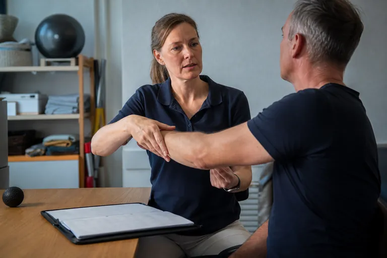 Physiotherapeutin behandelt einen Patienten mit Schulterbeschwerden