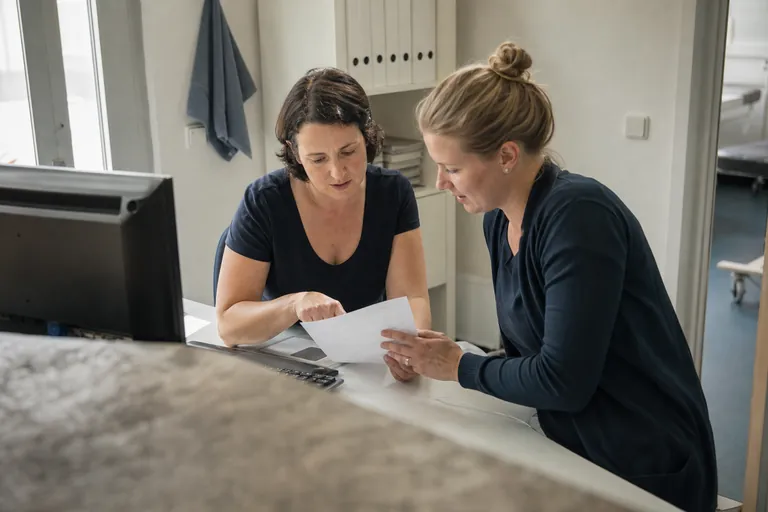 Mitarbeitende einer Ergotherapiepraxis prüfen Angaben auf einer Heilmittelverordnung